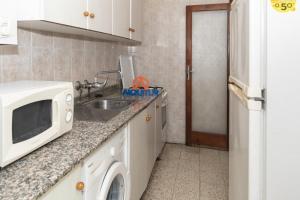 eine Küche mit einer Spüle und einer Mikrowelle in der Unterkunft Estirpe, 2º-3 in Cullera