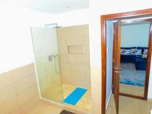 W łazience znajduje się prysznic ze szklanymi drzwiami. w obiekcie SWEET BREEZE HOMES w mieście Mombasa