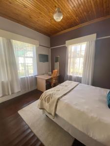 Un dormitorio con una cama, un escritorio y ventanas. en Foothills B&B, en Maseru