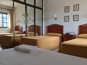 a hotel room with three beds and a mirror at Hotel Atalayas Extremadura in Zafra