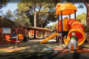 a boy sitting on a slide at a playground at Kampaoh Marbella in Marbella