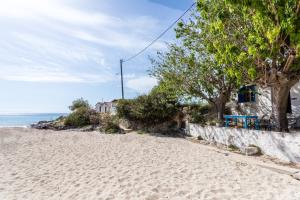 una playa de arena con árboles, una casa y el océano en Fisherman's Cottage en Stoupa
