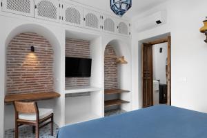 a bedroom with a bed and a tv on a wall at La AMARA Zaid - en el casco antiguo de Frigiliana in Frigiliana