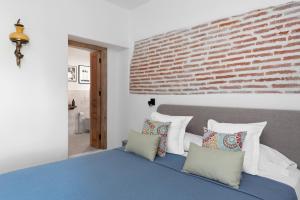 a bedroom with a brick wall and a bed with pillows at La AMARA Zaid - en el casco antiguo de Frigiliana in Frigiliana
