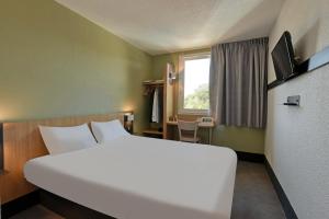 ein großes weißes Bett in einem Zimmer mit Fenster in der Unterkunft B&B HOTEL Brive-la-Gaillarde in Ussac