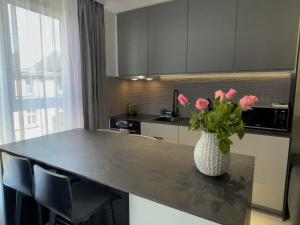 uma cozinha com uma mesa com um vaso com rosas cor-de-rosa em URBAN APARTMENTS PREMIUM DOWNTOWN Opolska 10 No 69 with GARAGE em Katowice