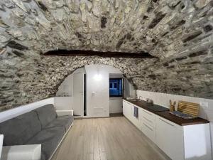 - un salon avec un canapé et un mur en pierre dans l'établissement Appartamento incantevole La Grotta, à Apricale