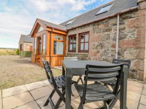 a table and chairs in front of a stone cottage at The Bothy in Peterhead