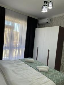 a bedroom with a bed with two towels on it at KERUEN SARAY APARTMENTS 27/2 in Türkistan