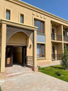 uma casa grande com um arco em frente em KERUEN SARAY APARTMENTS 27/2 em Türkistan