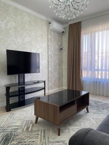 uma sala de estar com uma televisão e uma mesa de centro em KERUEN SARAY APARTMENTS 27/2 em Türkistan