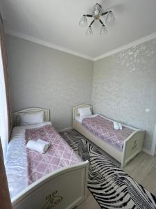 duas camas num quarto com rosa e branco em KERUEN SARAY APARTMENTS 27/2 em Türkistan