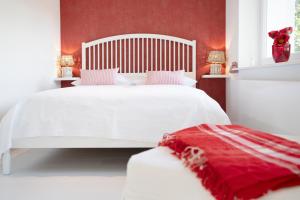 a bedroom with a white bed with a red wall at Golfplatz Plöner See "Kleiner Plöner See" in Bosau