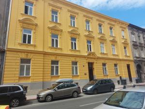 a yellow building with cars parked in front of it at Palma Apartment in Zagreb