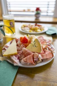een bord met vlees en kaas op een tafel bij Rifugio Chierego - 1911m in Brenzone sul Garda