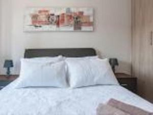 uma cama com lençóis brancos e almofadas num quarto em The Rand Haven em Midrand