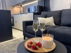 uma mesa com dois copos e uma vela e morangos em URBAN APARTMENTS PREMIUM DOWNTOWN Opolska 10 No 89 with GARAGE em Katowice