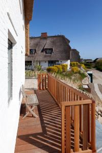 eine Holzterrasse mit einem Stuhl an der Seite eines Hauses in der Unterkunft Rantum Dorf - Ferienappartments im Reetdachhaus 3 & 4 in Rantum