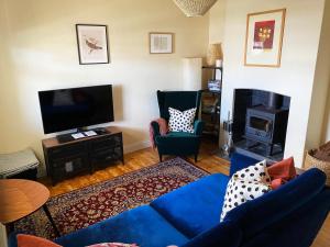 a living room with a blue couch and a tv at Wayfarers Cottage in Goolwa