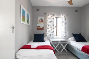 2 Betten in einem kleinen Zimmer mit Fenster in der Unterkunft The Bay 4 in Ballito