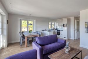 ein Wohnzimmer mit einem lila Sofa und einem Tisch in der Unterkunft Rantum Dorf - Ferienappartments im Reetdachhaus 3 & 4 in Rantum