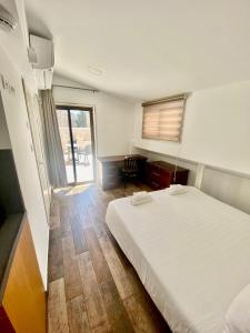 Petrakis Inn في القدس: غرفة نوم بسرير ابيض ونافذة