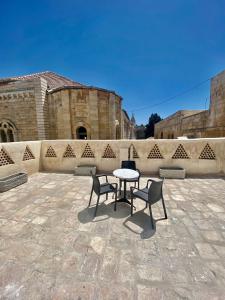 d'une terrasse avec une table, deux chaises et un mur. dans l'établissement Petrakis Inn, à Jérusalem