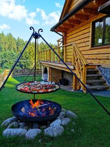a fire pit in front of a log cabin at Dom na Zielonym Wzgórzu z własną Sauną i Jacuzzi in Łapsze Niżne