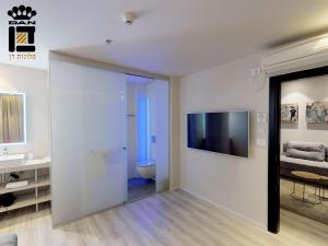 a bathroom with a toilet and a television on a wall at Link Hotel & Hub By Dan Hotels in Tel Aviv