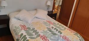 ein Bett mit einer Blumendecke darauf mit zwei Kissen in der Unterkunft APARTAMENTO CENTRO DE SANXENXO con GARAJE in Sanxenxo