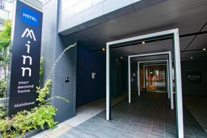 une entrée à un bâtiment avec un panneau sur celui-ci dans l'établissement Minn Nishi-Kasai, à Tokyo
