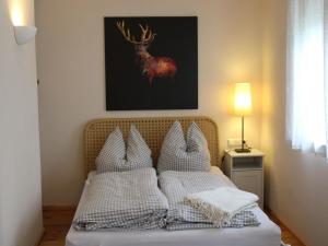- un lit avec des oreillers blancs et une photo de cerf dans l'établissement Lautertal Zinne, à Hayingen