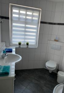 a bathroom with a sink and a toilet and a window at Fewo Aurora im Haus Nautilus in Wangerooge +10 photos
