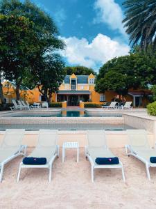 three lounge chairs and a pool in front of a house at Sirena Bay Estate in Willemstad