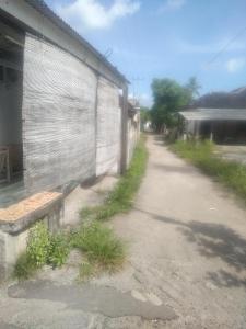 a dirt road next to a building with a wall at Family bungalow in Gili Meno
