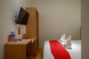 ein Hotelzimmer mit einem Bett und einem Fernseher in der Unterkunft RedDoorz Plus @ Losari Makassar in Makassar