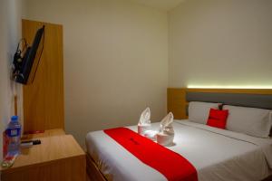 ein Schlafzimmer mit einem Bett mit einer rot-weißen Decke in der Unterkunft RedDoorz Plus @ Losari Makassar in Makassar