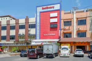 ein Redzone-Gebäude mit LKWs auf einem Parkplatz in der Unterkunft RedDoorz Plus @ Losari Makassar in Makassar
