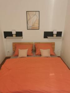 een slaapkamer met een oranje bed met 2 kussens bij Apartmán Bart's in Znojmo