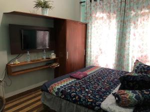 a bedroom with a bed and a flat screen tv at Inalum Permata Guest House 
