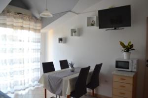 a dining room table with chairs and a tv on a wall at Apartmani Katarina in Brodarica