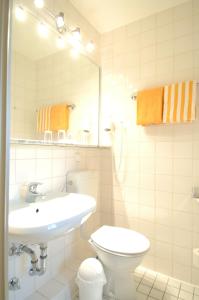 a bathroom with a sink and a toilet and a mirror at Haus Sparkuhl Hotel Garni in Hannover