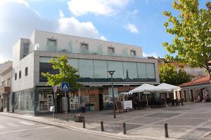 a large white building with tables and umbrellas on a street at Casa Avé Maria in Fátima