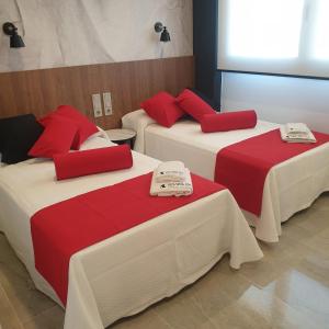 3 camas con colchas rojas y blancas en una habitación en Urbanlux Olimpia Sleep & More en Albacete