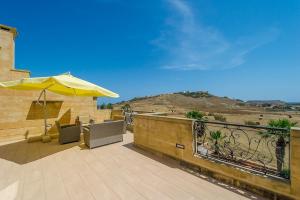 a patio with an umbrella and chairs on a balcony at Tfiefa Holiday Home in Xagħra