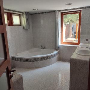 een badkamer met een bad, een wastafel en een raam bij Large house with parking, 30 min to Prague center in Úvaly