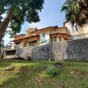 a house on a stone wall with a palm tree at Villa D3 Bukit Cijulang in Bogor