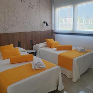 2 camas con almohadas de color naranja en una habitación en Urbanlux Olimpia Sleep & Park, en Albacete