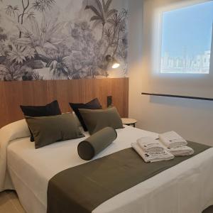 a bedroom with a large bed with two towels on it at Urbanlux Olimpia Familiar in Albacete