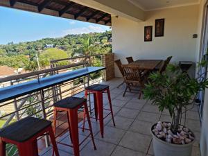 uma varanda com mesas e bancos e vista em Africatamna Self Catering House em Durban